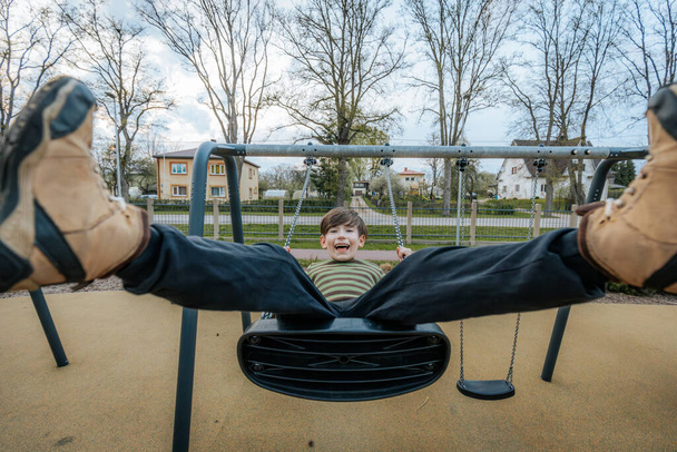boy is sitting on a swing. Smiling happy child - Foto, imagen