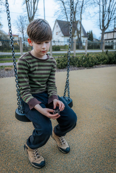 A boy is sitting on a swing. Smiling happy child - Foto, imagen