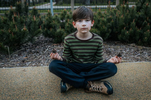 Мальчик сидит и медитирует. Ребенок отдыхает и медитирует. Улыбающийся счастливый ребенок - Фото, изображение