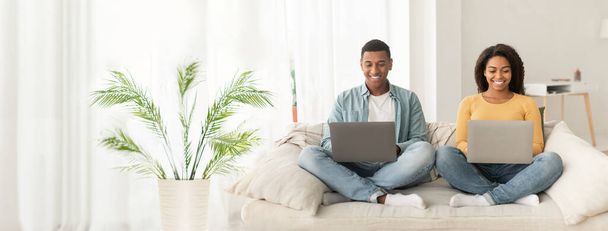 Χαλαρωμένο ζευγάρι Αφροαμερικανών με φορητό υπολογιστή, ιδανικό για web-banner με στόχο την απομακρυσμένη εργασία ή δραστηριότητες αναψυχής με χώρο αντιγραφής - Φωτογραφία, εικόνα