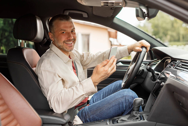 運転席に座っている間スマートフォンを使用してハッピー中年男性ドライバー,ナビゲーションシステムgpsを使用して - 写真・画像