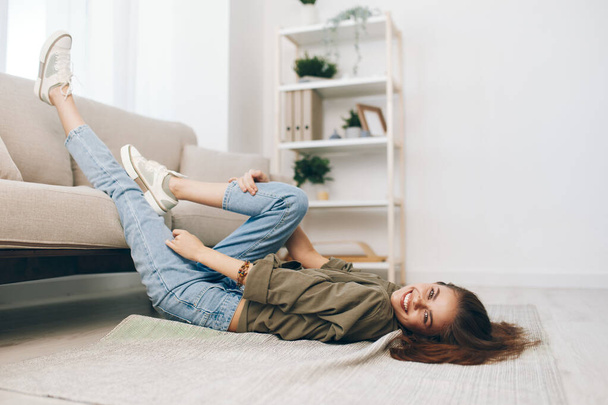 Άνετο, χαλαρωτικό διαμέρισμα: Μια ευτυχισμένη γυναίκα που βρίσκεται σε ένα σύγχρονο καναπέ σε ένα ήσυχο σαλόνι. - Φωτογραφία, εικόνα