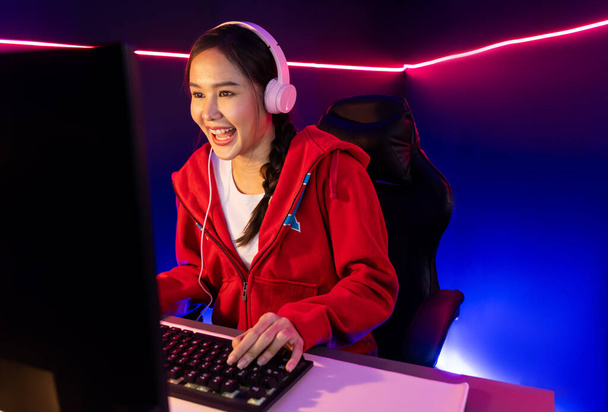 Host csatorna mosolygós gyönyörű ázsiai lány streamer játék online játék visel fejhallgató beszél a nézők média online rögzítő telefon. Esport képzett csapatjátékosok a neon kék szobában. Stratagem. - Fotó, kép