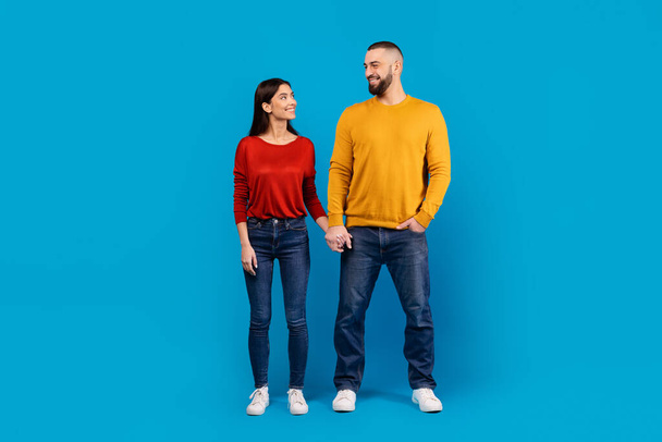 A man and a woman are standing side by side in the image. They are facing forward, appearing relaxed. Both individuals are dressed casually and are looking in the same direction. - Photo, Image