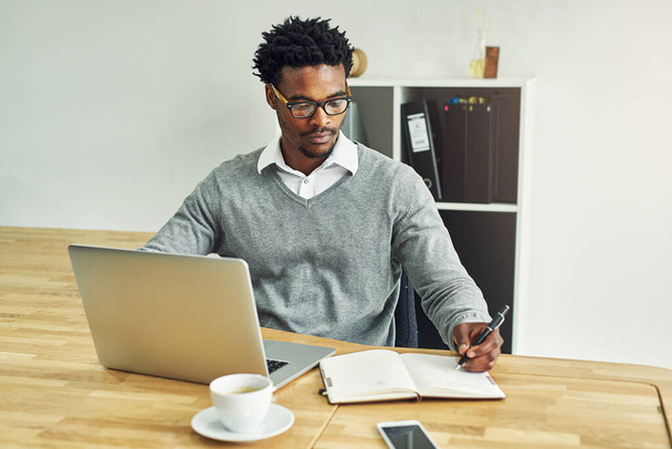 Negócios, homem negro e escrever no escritório com laptop para cronograma diário ou planejamento e definição de metas para gerenciamento de tempo. Empregado masculino, tecnologia séria e digital com revista para pesquisa - Foto, Imagem
