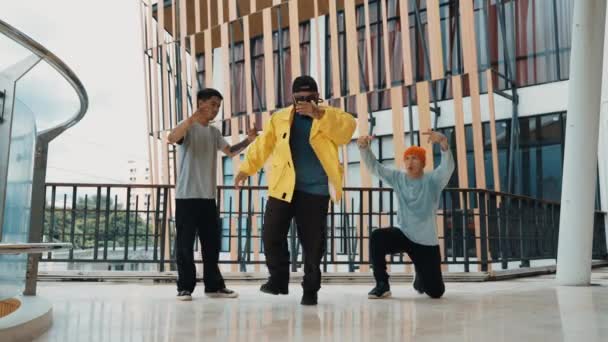 Ομάδα hipster κινείται βήμα προς τη μουσική hip-hop στο εμπορικό κέντρο διάδρομο. Εξειδικευμένη χορεύτρια διάλειμμα εκτελέσει b-boy χορό, ενώ περιβάλλεται από πολυπολιτισμική φίλο ή χορεύτρια ομάδα. Υπαίθριο άθλημα 2024. hiphop. - Πλάνα, βίντεο