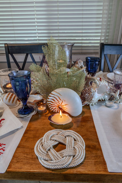 Tengeri kagyló és gyertya dekoráció tengerészeti asztal beállítás természetes színekkel és mélykék. - Fotó, kép