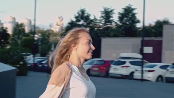 Ευτυχισμένη ξανθιά γυναίκα που χορεύει μια καλοκαιρινή μέρα. Χρηματιστήριο. Χαμογελώντας νεαρή κοπέλα στο δρόμο της πόλης - Πλάνα, βίντεο
