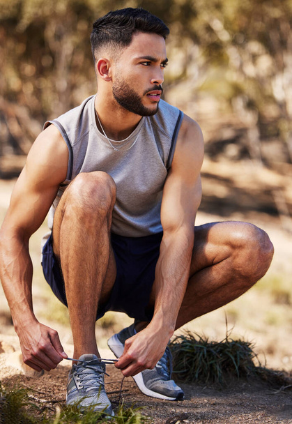 Man, runner and tying laces in outdoors, prepare and ready for workout or nature fitness. Male person, athlete and sneakers for jog or marathon training, gear and footwear for sports or wellness. - Photo, Image
