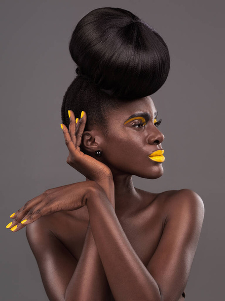 African, model and studio face with creative, beauty and cosmetic yellow lipstick. Bold, woman and skin with confidence, dramatic hair and bun for glamour or trendy makeup isolated on grey background. - Photo, Image