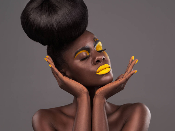 Afrikanisch, Frauen- und Studiokunst mit Make-up, Schönheit und kreativem gelben Lippenstift. Kühn, Model und Haut mit Selbstbewusstsein, dramatisches Haar und Dutt für Glamour oder trendige Kosmetik auf isoliertem grauen Hintergrund. - Foto, Bild
