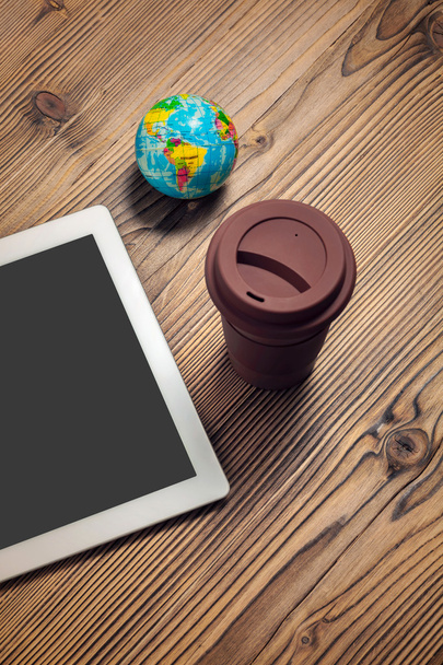 tablet computer, coffee cup and globe on wood table - Photo, Image