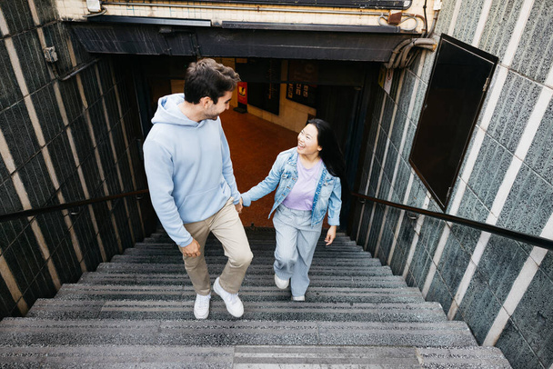 Interracial alegre pareja en una cita, bajando del metro en una ciudad. - Foto, Imagen