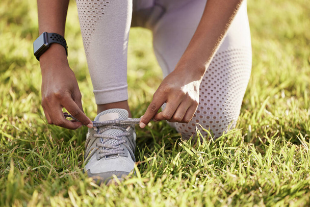 Grass, hands and tie shoes for fitness, training or start exercise outdoor in nature in summer. Legs, person and tying sneakers lace on lawn at garden to prepare for sport, workout or running closeup. - Photo, Image