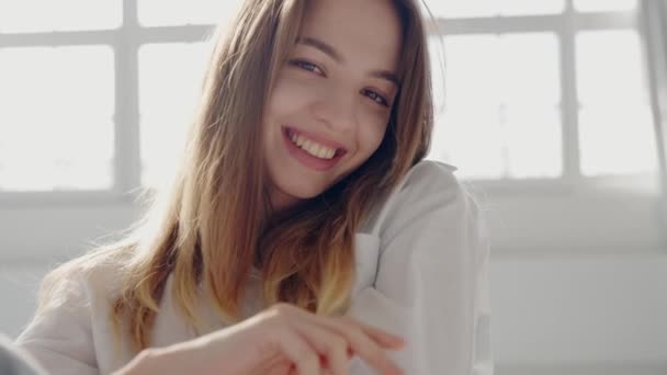 Portrait of a cheerful, young woman with a radiant smile, enjoying a sunny day indoors. Her expression conveys happiness and positivity. Happy Young Woman with a Bright Smile in Natural Light - Footage, Video