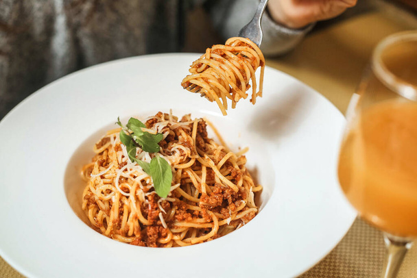 Eine Person hält eine Gabel voller Spaghetti fest vor dem Mund. - Foto, Bild