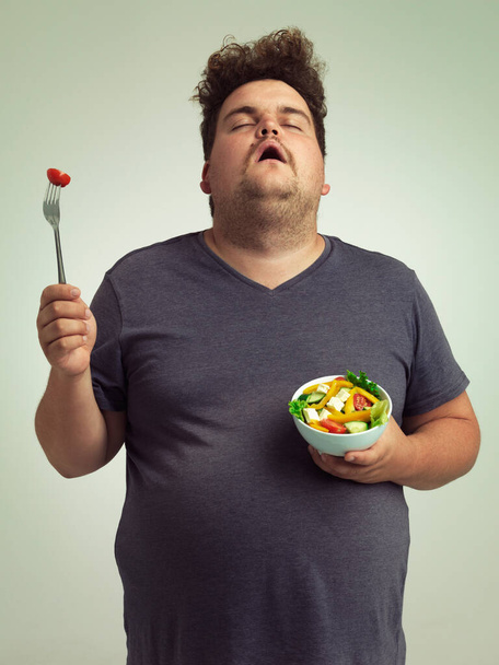 スタジオのバックグラウンドに健康的なフォーク,ボウル,野菜を備えた健康的な食べ物とサイズの男,サラダ,ダイエット. 男性, イライラし,健康のための体重を減らす, 障害や栄養を食べる. - 写真・画像