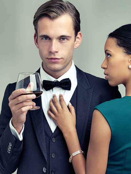 Alcohol, fashion and portrait of couple in studio with elegant, formal and stylish clothes for event. Luxury, party and man and woman with drink and confidence, pride and glamour on gray background. - Photo, Image