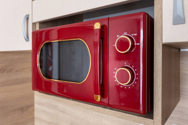 Modern vörös mikrohullámú sütő ételkészítéshez a konyhaszekrényen, szekrényen - Fotó, kép