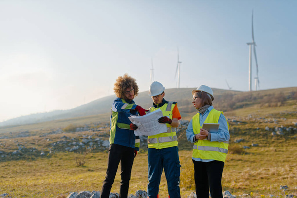 A team of engineers and workers oversees a wind turbine project at a modern wind farm, working together to ensure the efficient generation of renewable energy.  - Photo, Image