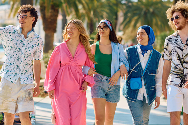 Різноманітна група туристів, одягнена в літній одяг, прогулюється по туристичному місту з широкими посмішками, насолоджуючись своїми екскурсійними пригодами.  - Фото, зображення