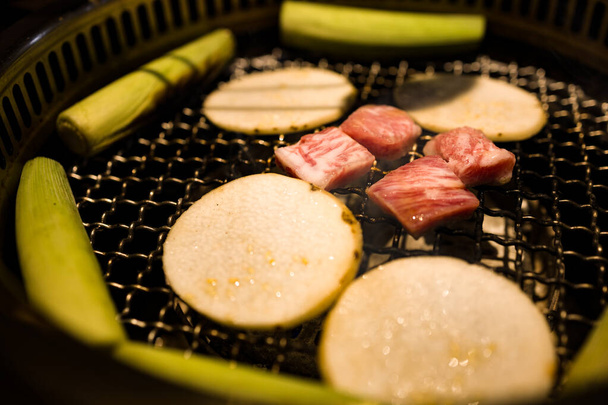  a grill where freshly prepared meat slices and vegetables are being cooked - Photo, Image