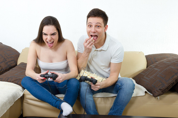 couple in love on sofa sitting and playing video games in living - Photo, Image