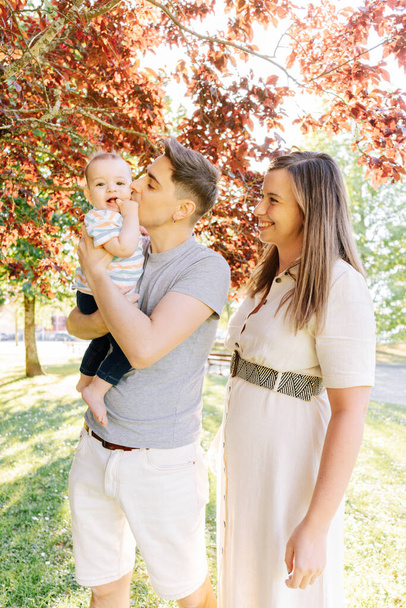 Retrato de una familia joven con su bebé de nueve meses divirtiéndose en el parque público - Foto, imagen