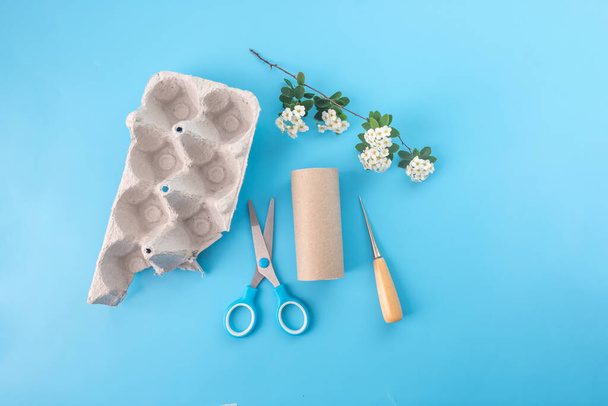 Natural materials for childrens creativity. empty toilet paper roll, egg carton box, white flowers, scissors and awl - Photo, Image