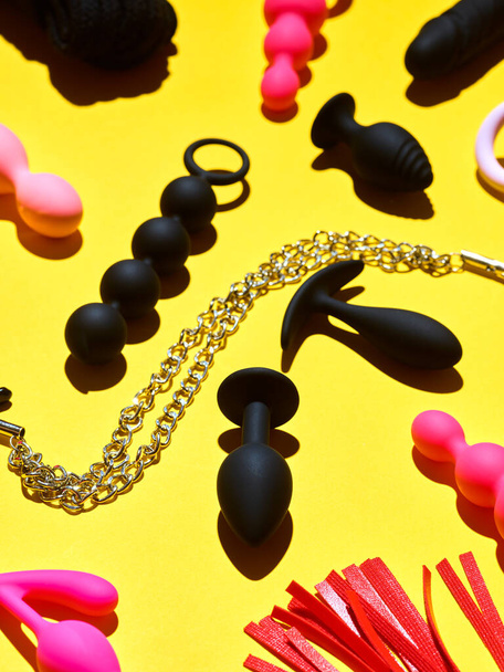 Bright sex toys background. anal plugs and dildo over yellow paper backdrop - 写真・画像