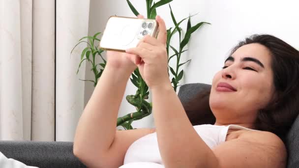 nainen ottaa selfie hänen älypuhelin sohvalla. - Materiaali, video