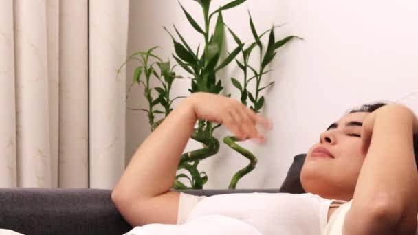 νεαρή γυναίκα που τεντώνεται στο κρεβάτι στο σπίτι - Πλάνα, βίντεο