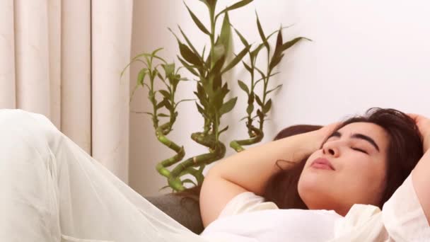 giovane donna sdraiata a letto e stretching - Filmati, video