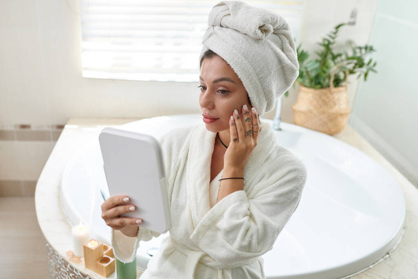 Mujer aplicando suero facial después de tomar el baño - Foto, Imagen