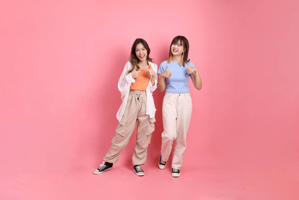 Young adults friends, 20s East Asian women thumbs up on the pink background.  - Photo, Image