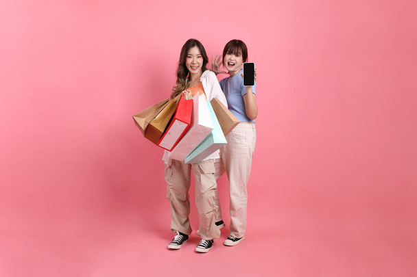 Jóvenes adultos amigos, 20s mujeres de Asia Oriental sosteniendo bolsa de compras en el fondo rosa.  - Foto, imagen