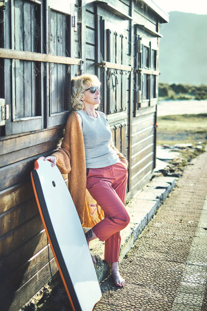 Genç, sarışın, beyaz bir kadının portresi plaj bölgesine yakın, güneş gözlüklü, tahta bir evde. Berria plajı, Cantabria, İspanya, Avrupa. - Fotoğraf, Görsel