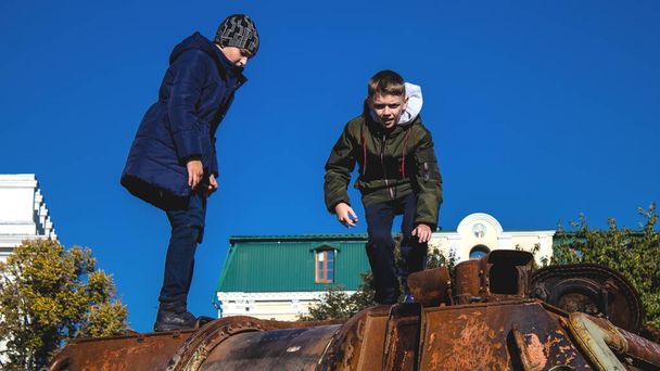 Oekraïense kinderen hebben plezier op de vernietigde Russische militaire uitrusting, ze gebruiken het als een speeltuin. De vernietigde Russische militaire uitrusting tentoonstelling is een openlucht tentoonstelling. - Foto, afbeelding