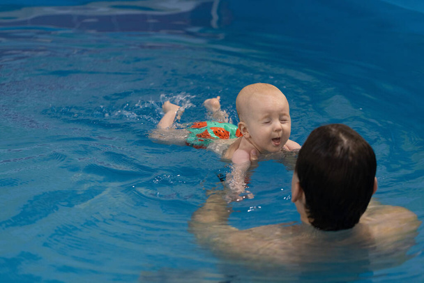 Das Baby atmet durch und schließt die Augen, bevor es unter Wasser taucht - Foto, Bild