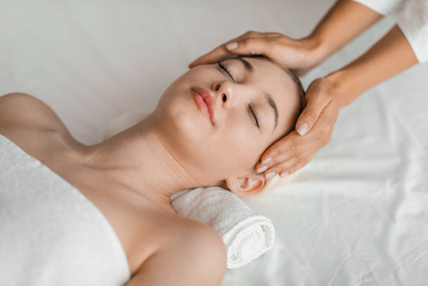 Una giovane bionda gode di un rilassante massaggio facciale in una spa, incarnando serenità e tranquillità in un ambiente rilassante - Foto, immagini