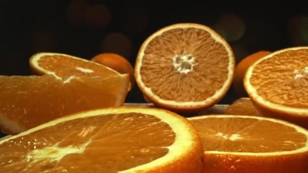 Una captura macrográfica de una rebanada de naranja, colocada sobre un fondo negro elegante y aislado, se despliega como una obra maestra visual de encanto cítrico. Una rebanada de naranja con fondo negro. Comestible. - Metraje, vídeo