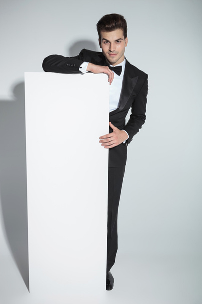 Elegant business man leaning on a white board - Fotó, kép