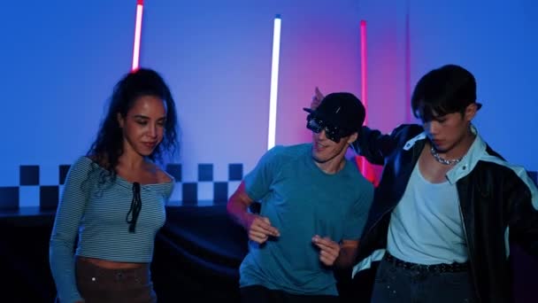 Diverse street dancer moving to city pop music at party with neon light while man wearing fancy glasses. Attractive hipster perform or practicing dancing together while looking at camera. Regalement. - Footage, Video