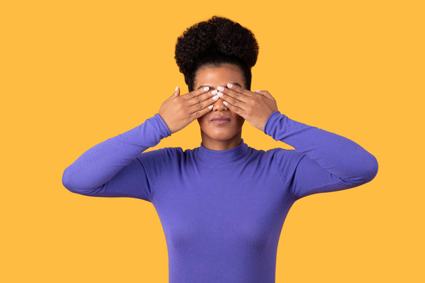 A woman is shown covering her eyes with her hands in this straightforward image. She appears to be blocking out light or shielding her eyes from something. - Photo, Image