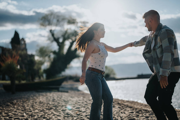 Szczęśliwa para dzieli taniec na spokojnej plaży, ich radosne wyrażenia uchwyciły istotę idealnego wspólnego wypoczynku. - Zdjęcie, obraz