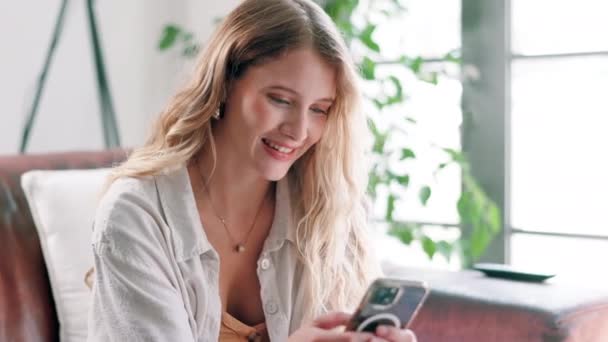 Woman, cellphone and laughing for internet at home for digital communication, networking or scroll. Female person, sofa and smartphone or reading social media in apartment or relax, search or online. - Footage, Video