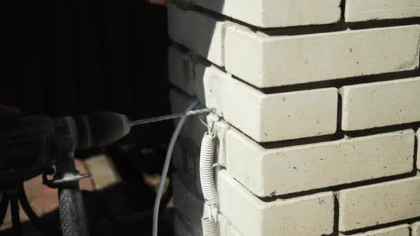 Costruttore Pratica un foro nel muro con un trapano a martelli. Primo piano di martello perforatore perforatore fare foro - Filmati, video