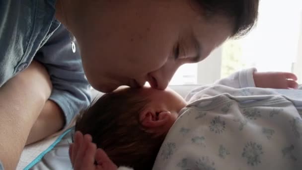Schattige moeder scène van moeder zoenen pasgeboren baby door venster thuis tijdens de eerste dagen van het leven van zuigeling zoon - Video