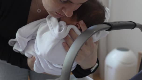 Madre poniendo al bebé recién nacido en un asiento portátil con cuidado suave. padre atento cuida a su bebé durante los primeros días de vida - Metraje, vídeo