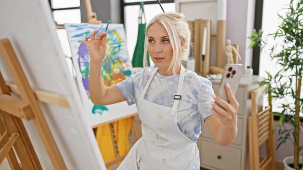 Spunky młody blond artysta rysuje podczas wideokonferencji w przytulnym studio sztuki, łącząc kreatywność i technologię - Zdjęcie, obraz
